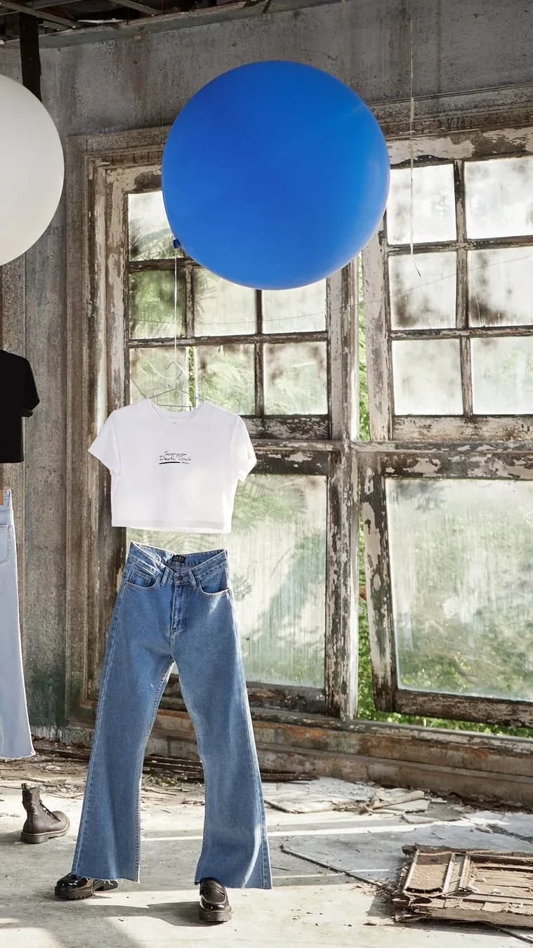 A Jack Russel denim outfit suspended beneath an oversized blue balloon in a derelict room
